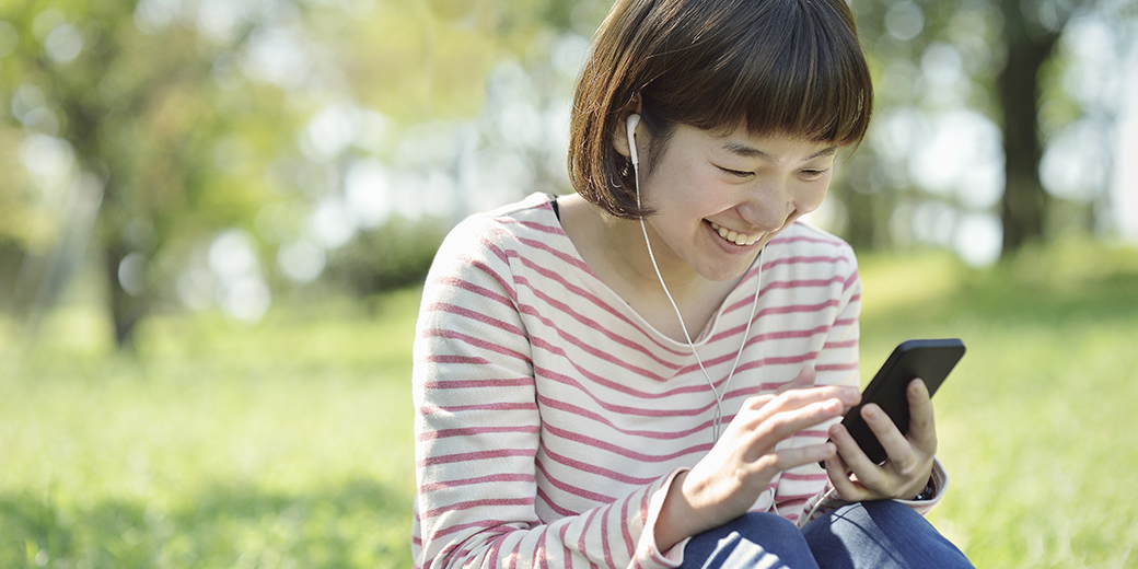 a woman in a park using mobile device and headphones