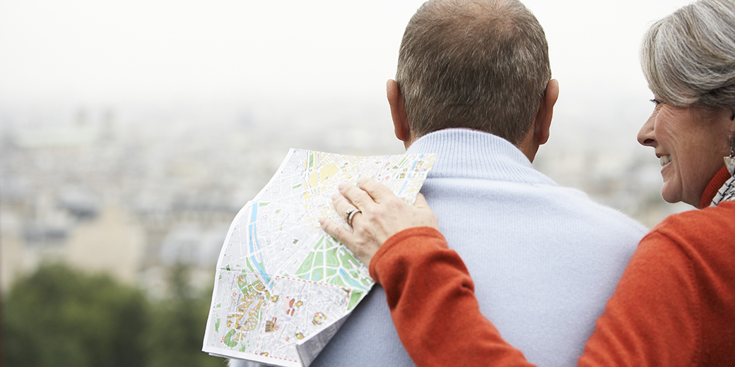a senior couple looking at distant view and holding a map