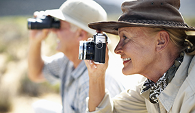 a senior couple wearing safari hats and using cameras