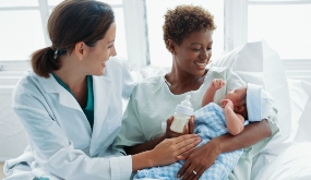 physician assisting patient holding a baby