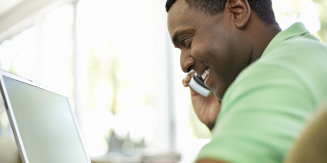 a man on his phone using a laptop