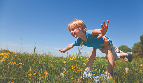 a man in a meadow holding child aloft