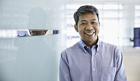 a man standing in a Chevron office hallway and smiling at camera