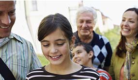 a child walking with family, including grandparent in the background