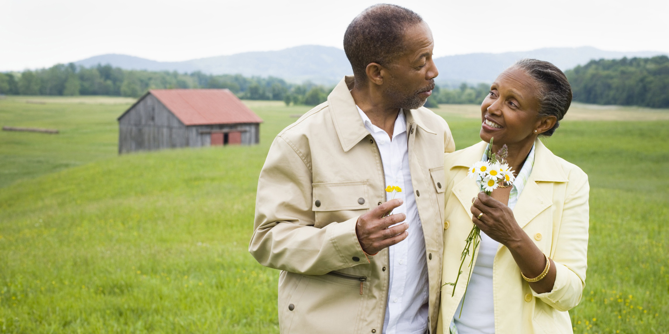 a man and woman holding flowers with a prairie in the background