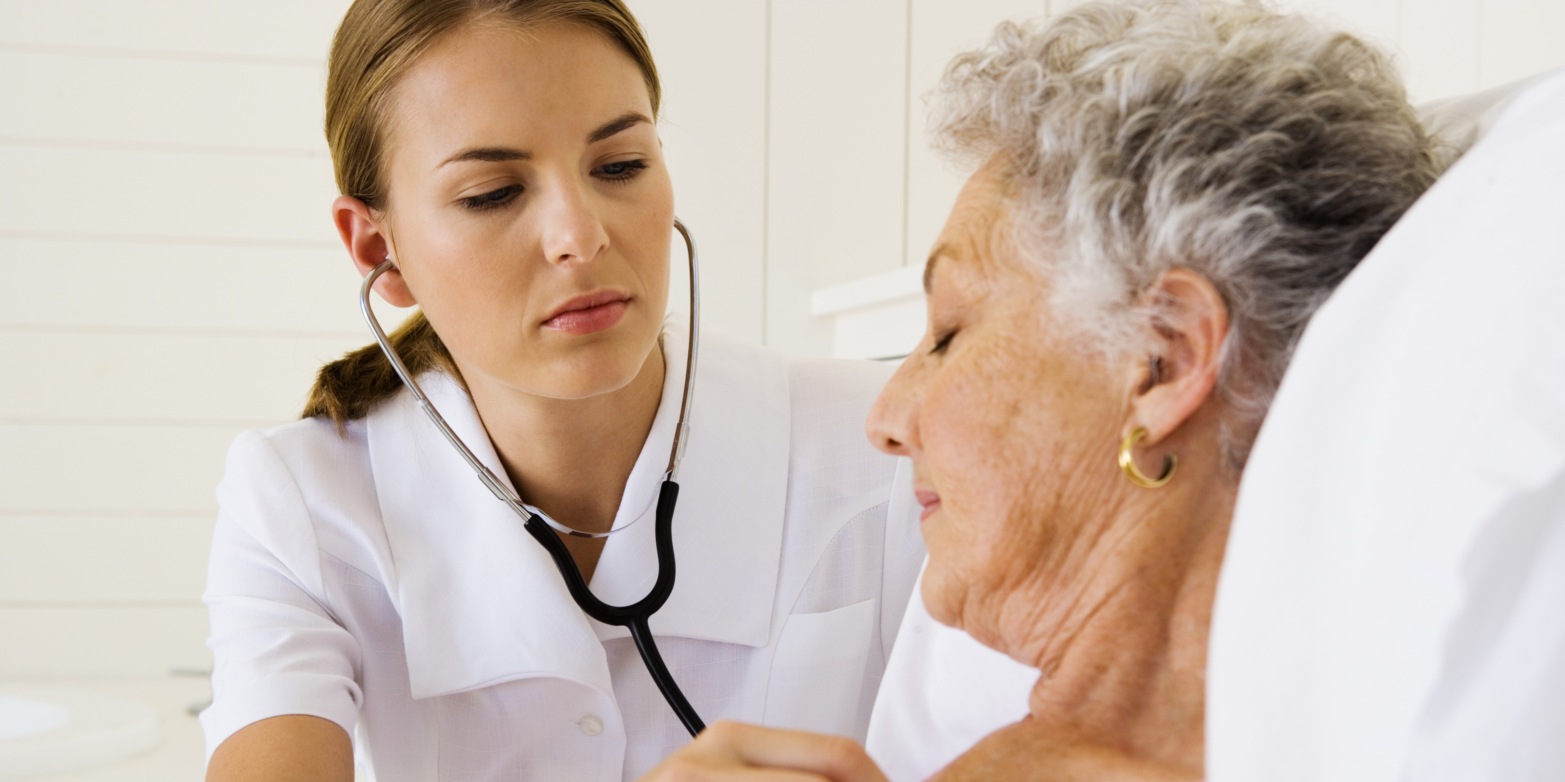 health practitioner using stethoscope to evaluate senior woman
