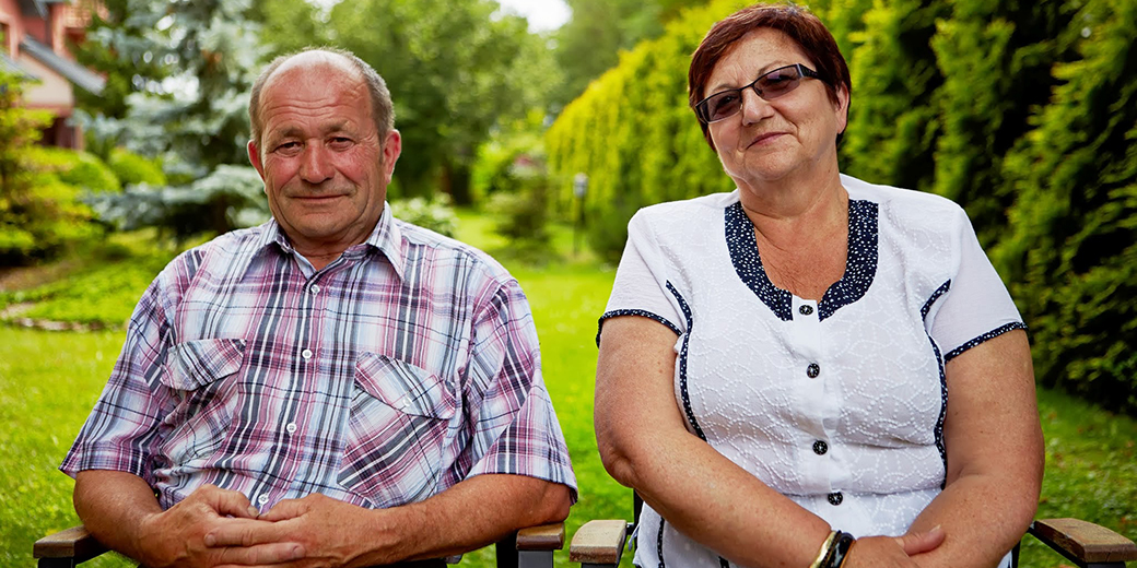 an older man and woman sitting in a garden