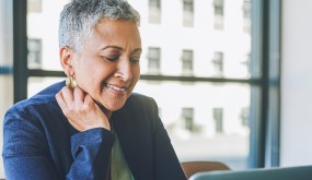 Woman retiree smiling and looking at a laptop