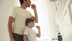 a father and son brushing teeth