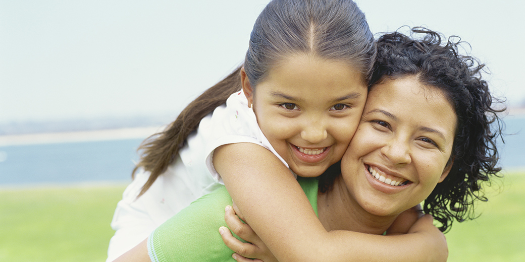 a girl holding on to woman on piggyback