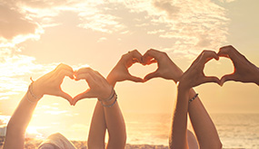 three people holding hands up forming a heart shape