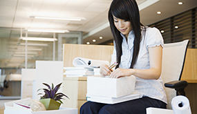 a woman in an office sorting through a box of files