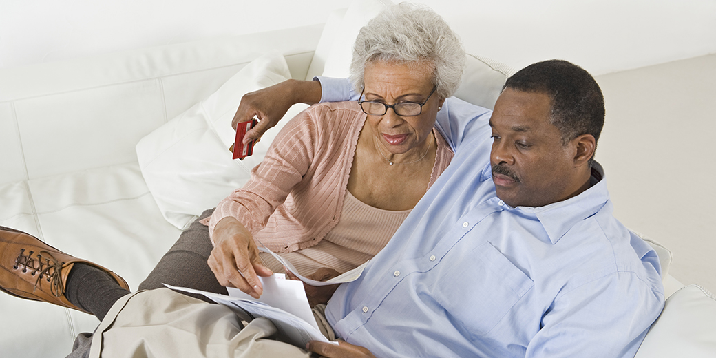 a middle aged couple sitting on a couch and looking at documents