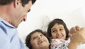 a man and two girls smiling on sofa