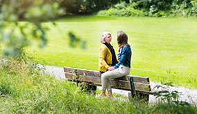 mother and daughter sitting on park bench