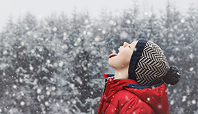 boy catching snowflakes with his tougue