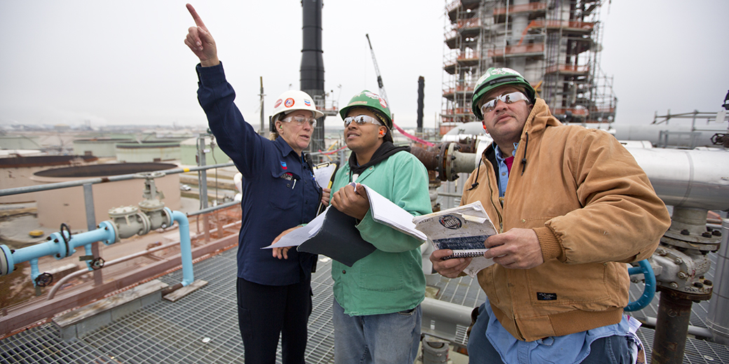 chevron workers on-site holding documents and looking up