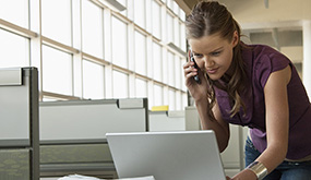 lady looking at her computer and on the phone