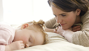 woman looking over sleeping baby