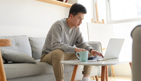 a man sitting in living room using laptop