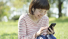 woman sitting on lawn and using mobile device