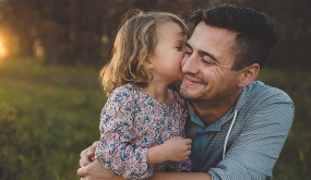 man sitting outdoors hugging a child